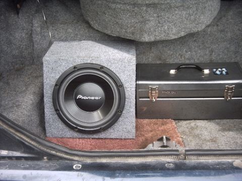 1990 Ford Crown Victoria LTD - A car's trunk space contains a subwoofer and a toolbox, with visible text on the toolbox.