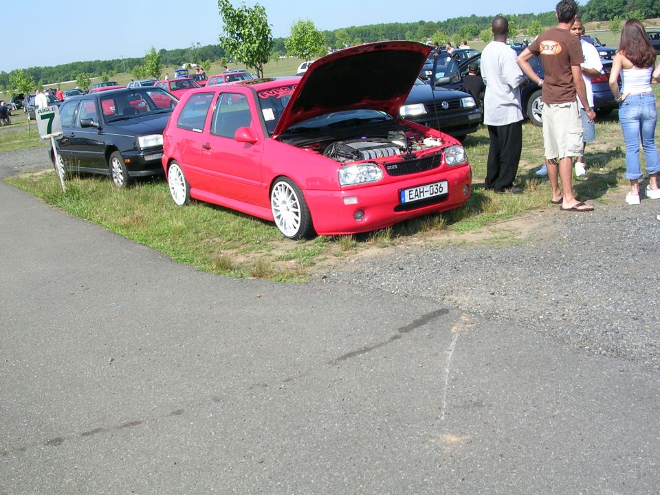 Red hatchback car with white rims and hood open, showing engine. License plate EAH-036