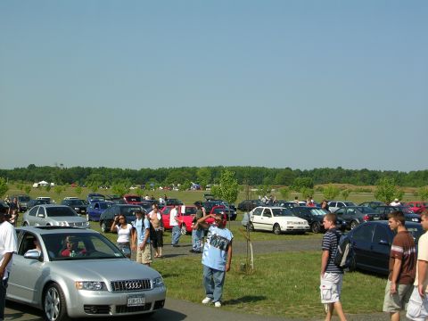 1990 Jeep YJ - A gathering of vehicles in an outdoor lot under a clear blue sky.