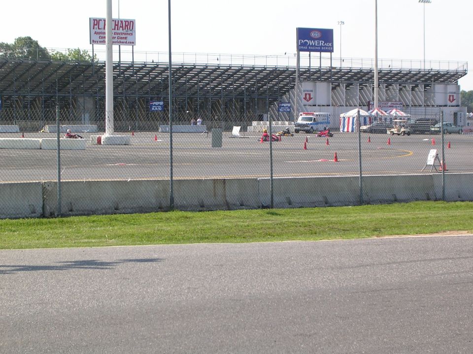 Go-karts race on a track with a van and tents in the background