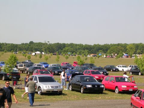 1990 Jeep YJ - A gathering of cars and people in an open field on a sunny day.