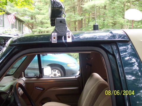 1994 Ford Bronco - A light bar is mounted to the roof of a dark green vehicle, with a blue minivan seen through the passenger window.