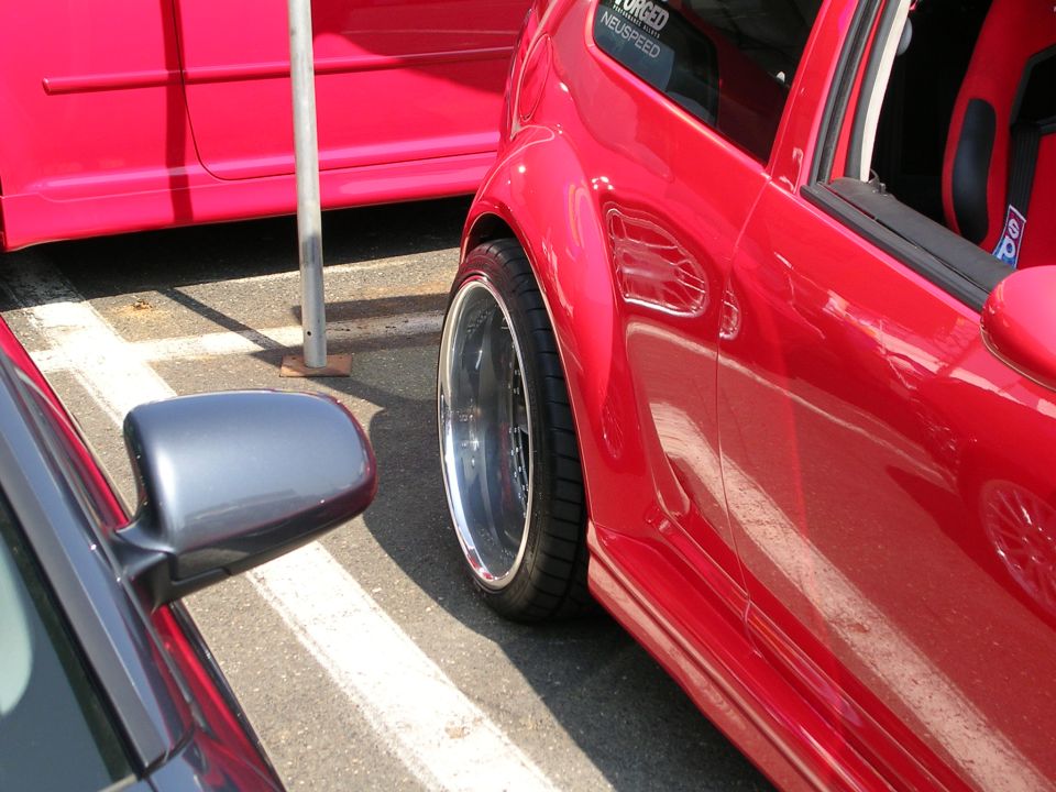 Close-up of a red sports car's fender and wheel, parked next to another car