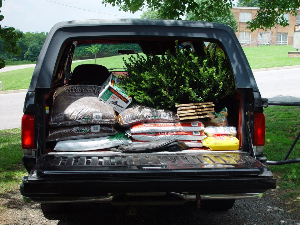 Black Ford Bronco with tailgate down loaded with mulch, topsoil bags and a shrub