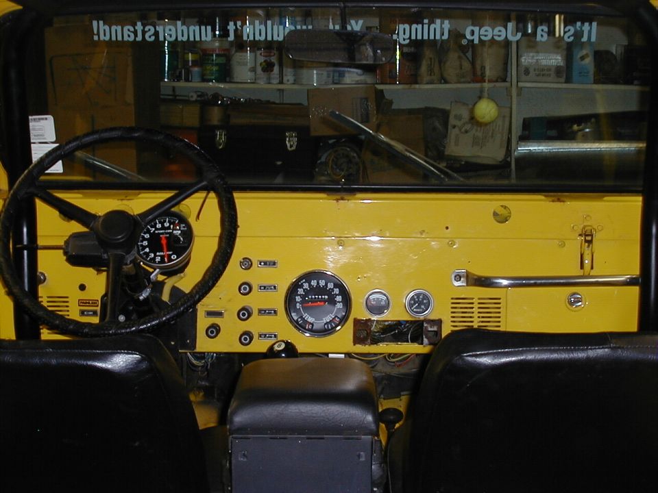 Yellow Jeep CJ dash with center speedometer, toggle switches and column-mounted tachometer