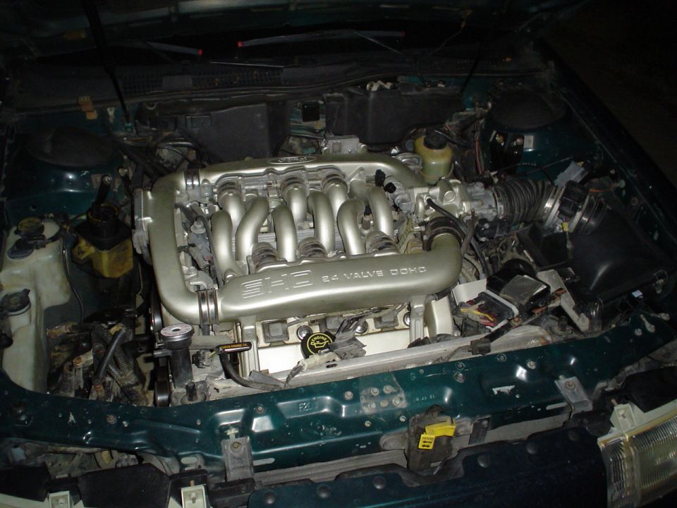 Engine bay of a green car with a SHO 24 Valve DOHC intake manifold under the hood