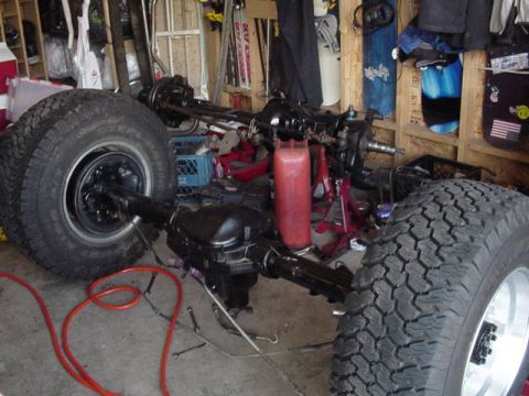 1987 Ford Bronco - Front axle assembly and tires are laid out in a garage, likely for repair or modification.