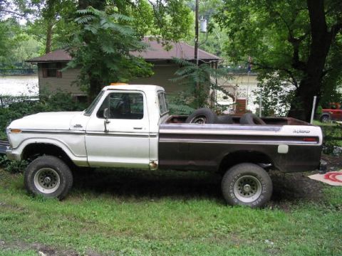 1979 Ford F-250 - A two-tone 1979 Ford F-250 pickup truck sits in a grassy yard next to a house, with a red vehicle visible in the background.