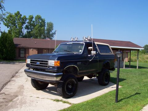 1989 Ford Bronco - This lifted Ford Bronco is parked in front of a house on a sunny day.