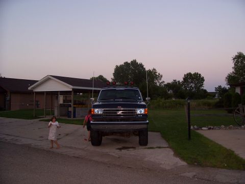 1989 Ford Bronco - A dark blue Ford F-Series truck is parked in a driveway with two children in the foreground.