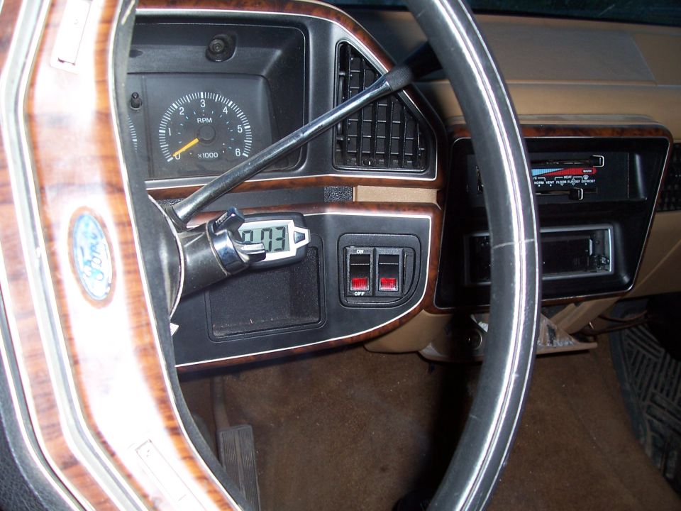 Woodgrain steering wheel and dash of 1989 Ford Bronco with tachometer, column-mounted digital gauge, and rocker switches