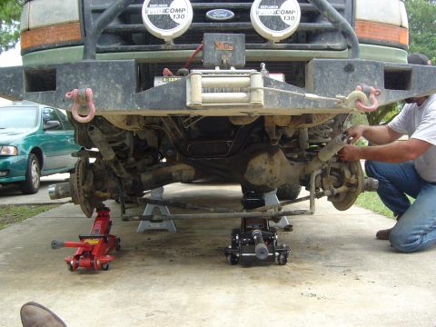 1993 Ford Bronco - Front suspension of a 1993 Ford Bronco is lifted on jack stands for maintenance, a winch and auxiliary lights on the bumper.
