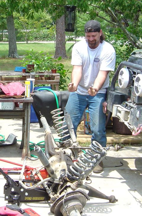 1993 Ford Bronco - Disassembled vehicle suspension components are laid out on the ground next to a man.