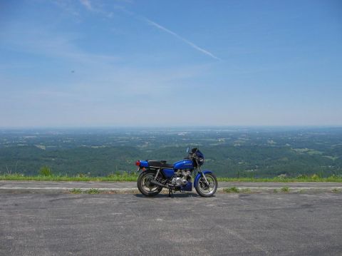 1985 Ford LTD Crown Victoria - A blue motorcycle is parked at a scenic overlook on a clear day.