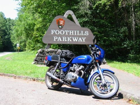 1985 Ford LTD Crown Victoria - Motorcycle parked beside the entrance sign for Foothills Parkway.