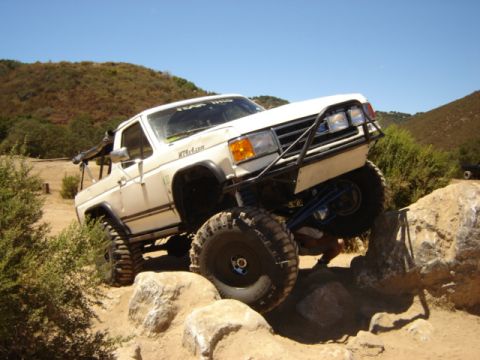 1991 Ford Bronco - Modified 1991 Ford Bronco tackling a rocky obstacle on an off-road trail.