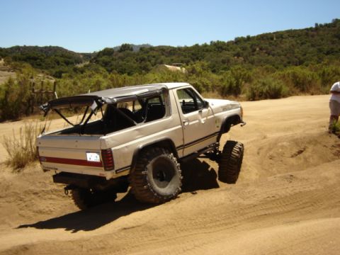1991 Ford Bronco - This lifted SUV navigates a sandy terrain with a clear blue sky overhead.