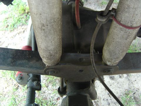 1993 Ford Bronco - Underside close-up of a solid axle housing showing the differential cover flanked by a leaf spring and U-bolt spring pack plate, with a pai…