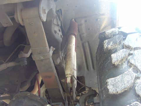 1993 Ford Bronco - Underside view of a Ford Bronco showing suspension components, including a red-and-silver shock absorber, coil spring, control arms, and a…
