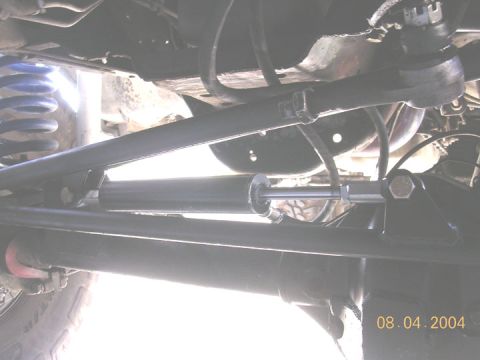 1994 Ford Bronco - Underside view of a vehicle's steering system components, including tie rods and a steering stabilizer.