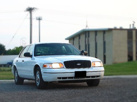 2000 Ford Crown Victoria - A white 2000 Ford Crown Victoria is parked in front of a building.