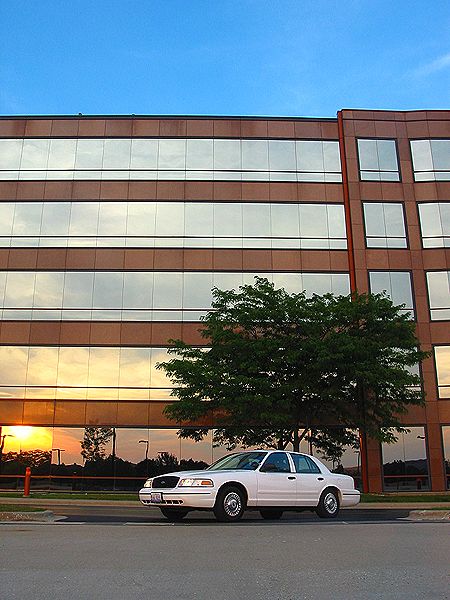 2000 Ford Crown Victoria - A white 2000 Ford Crown Victoria is parked outside an office building during sunset.