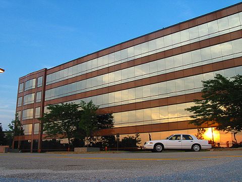 2000 Ford Crown Victoria - A white sedan is parked in front of a modern office building during sunset.