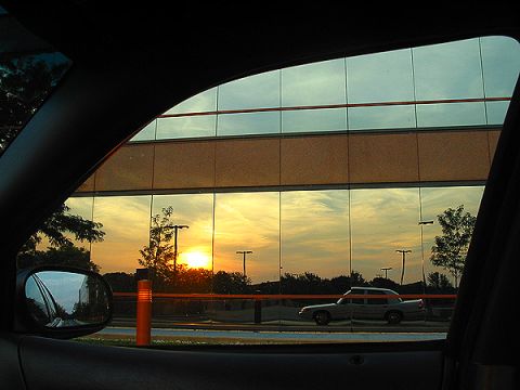2000 Ford Crown Victoria - A sedan, likely a 1998 Ford Crown Victoria, is parked outside a building as the sun sets, casting reflections on the windows.