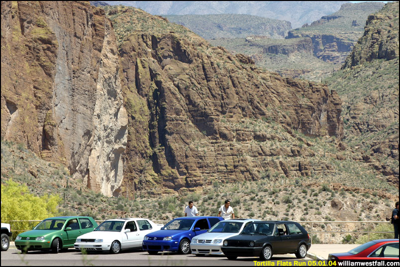 Several Volkswagen Golfs parked in a desert canyon with rocky cliffs