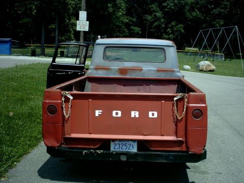 1954 Ford F-100 - This Ford pickup truck has a red body and a gray cab. The tailgate is down, showing the Ford lettering.