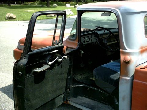 1954 Ford F-100 - The interior of a 1954 Ford F-100 truck is visible through the open driver's door.