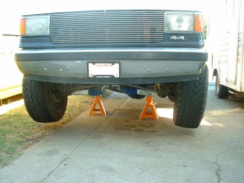 1990 Ford Bronco - This 1990 Ford Bronco is shown from the front, elevated on orange jack stands, revealing its lifted suspension and 4x4 badging.