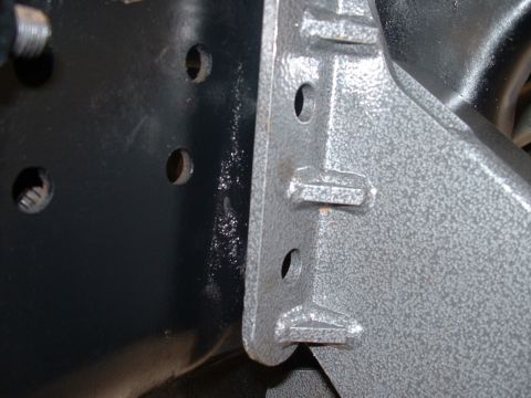 1990 Ford Bronco - A close-up view of a vehicle's frame and a bolted-on bracket, showing mounting holes.