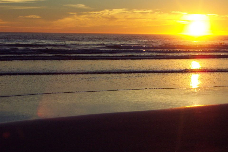 Golden sunset over the ocean reflecting on wet sand and rolling waves