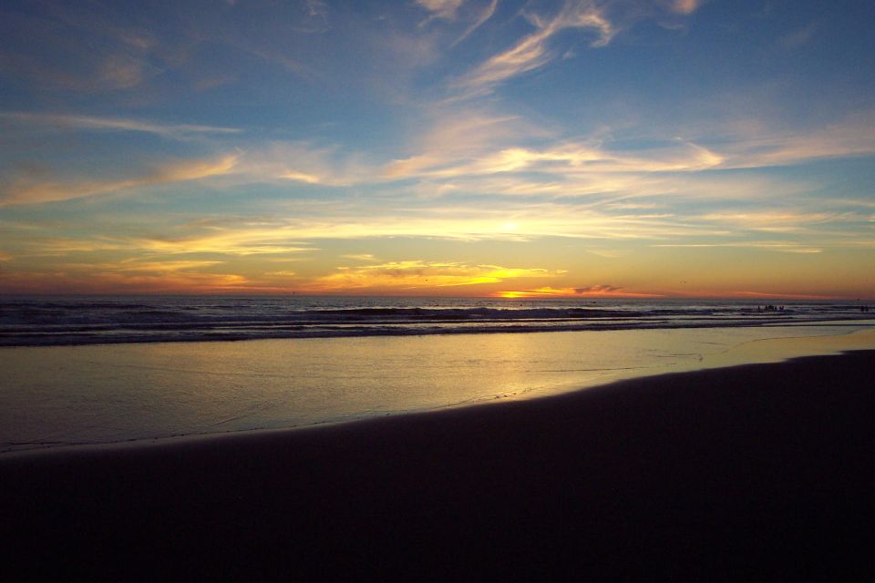 Blue and orange ocean sunset with low sun and reflection on the smooth wet beach