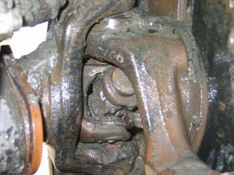 1985 Ford Bronco - Detail view of heavily soiled and corroded vehicle suspension components, likely a ball joint assembly.