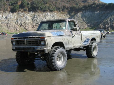 1985 Ford Bronco - This lifted pickup truck is covered in mud after driving on the beach.