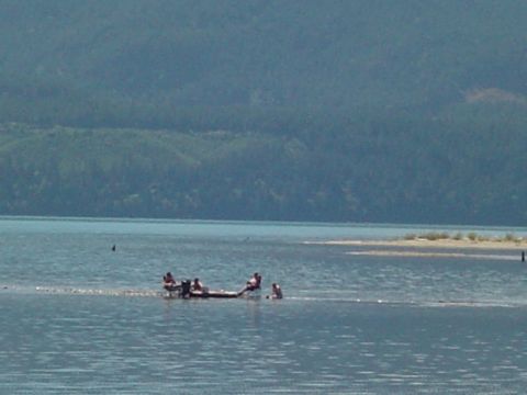 1993 Ford Bronco - A boat carrying several people travels across a calm lake, with a forested hillside visible in the distance.