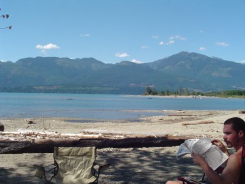 1993 Ford Bronco - A man relaxes by the water, enjoying a newspaper amidst a scenic mountain backdrop.