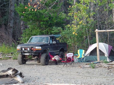 1993 Ford Bronco - A lifted 1993 Ford Bronco is parked at a campsite next to a tent and chairs.