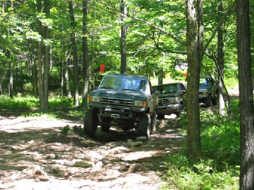 Dark green Ford Bronco with a winch on the front bumper driving on a rocky trail