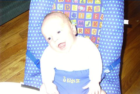 1995 Ford Bronco - Baby sitting in a bouncer with alphabet blocks pattern and 'Kids II' on clothing.