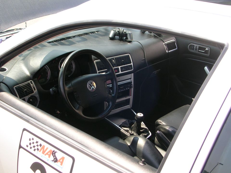 Interior of a Volkswagen with a manual shifter and racing decals on the door