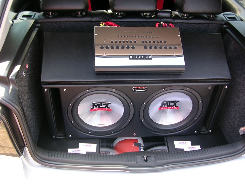 Car trunk with two MSX Audio subwoofers and an xtant amplifier. Fire extinguisher visible