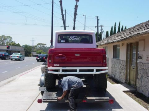 1992 Ford Bronco - A red 1992 Ford Bronco with a white roof is being loaded onto a trailer, showing the rear and the '351' badge.