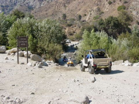1992 Ford Bronco - Off-road vehicles navigate a dirt path near a "Cross Stream Here" sign.