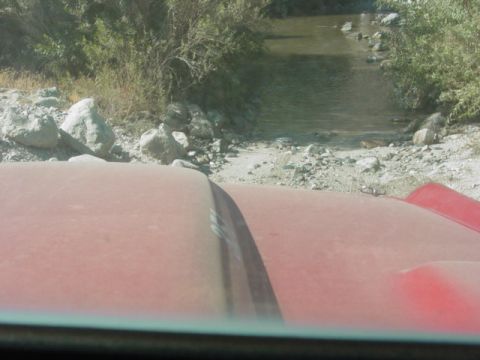 1992 Ford Bronco - Driving a red SUV through a rocky stream bed on a sunny day.