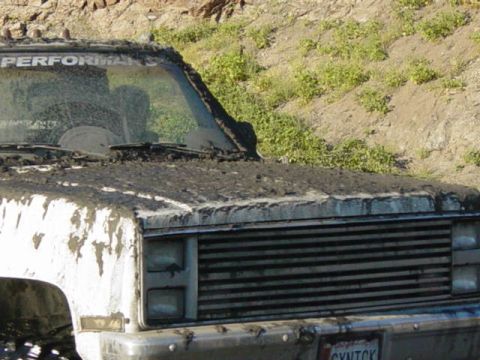 1992 Ford Bronco - This white pickup truck is heavily covered in mud, obscuring most of its details.