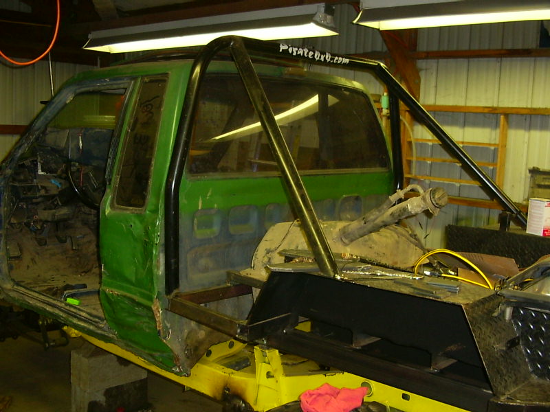 Green truck cab with roll cage, stripped interior, and custom fabrication in progress