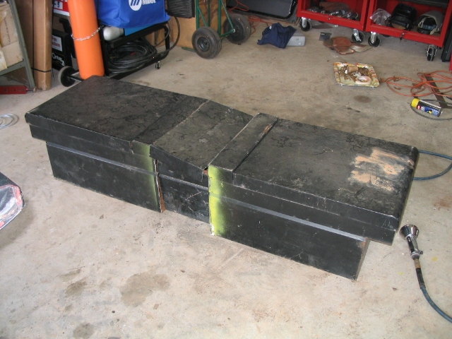 Three black metal toolboxes on a concrete floor in a garage